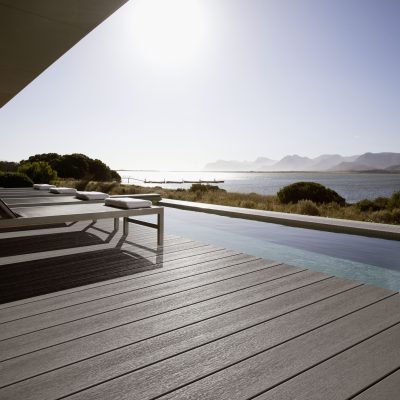 View of sun shining on lake from patio with swimming pool